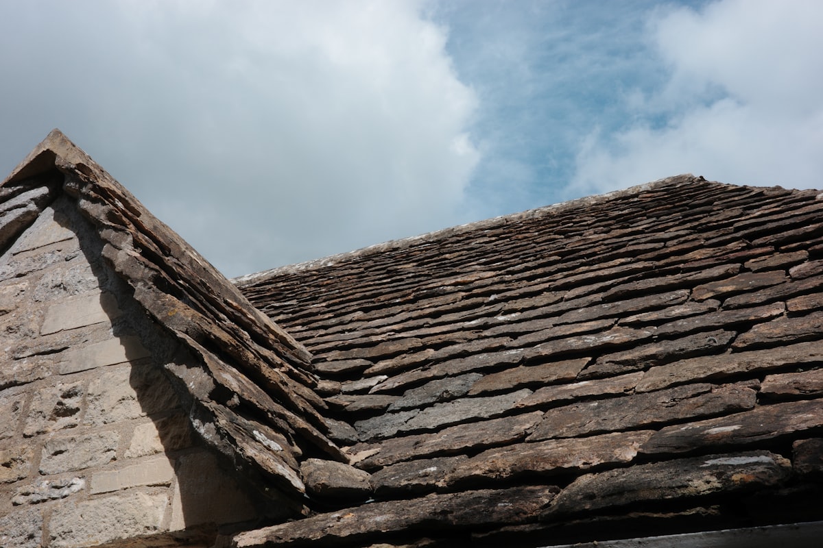 Weathered Welsh slate roof tiles against a cloudy sky